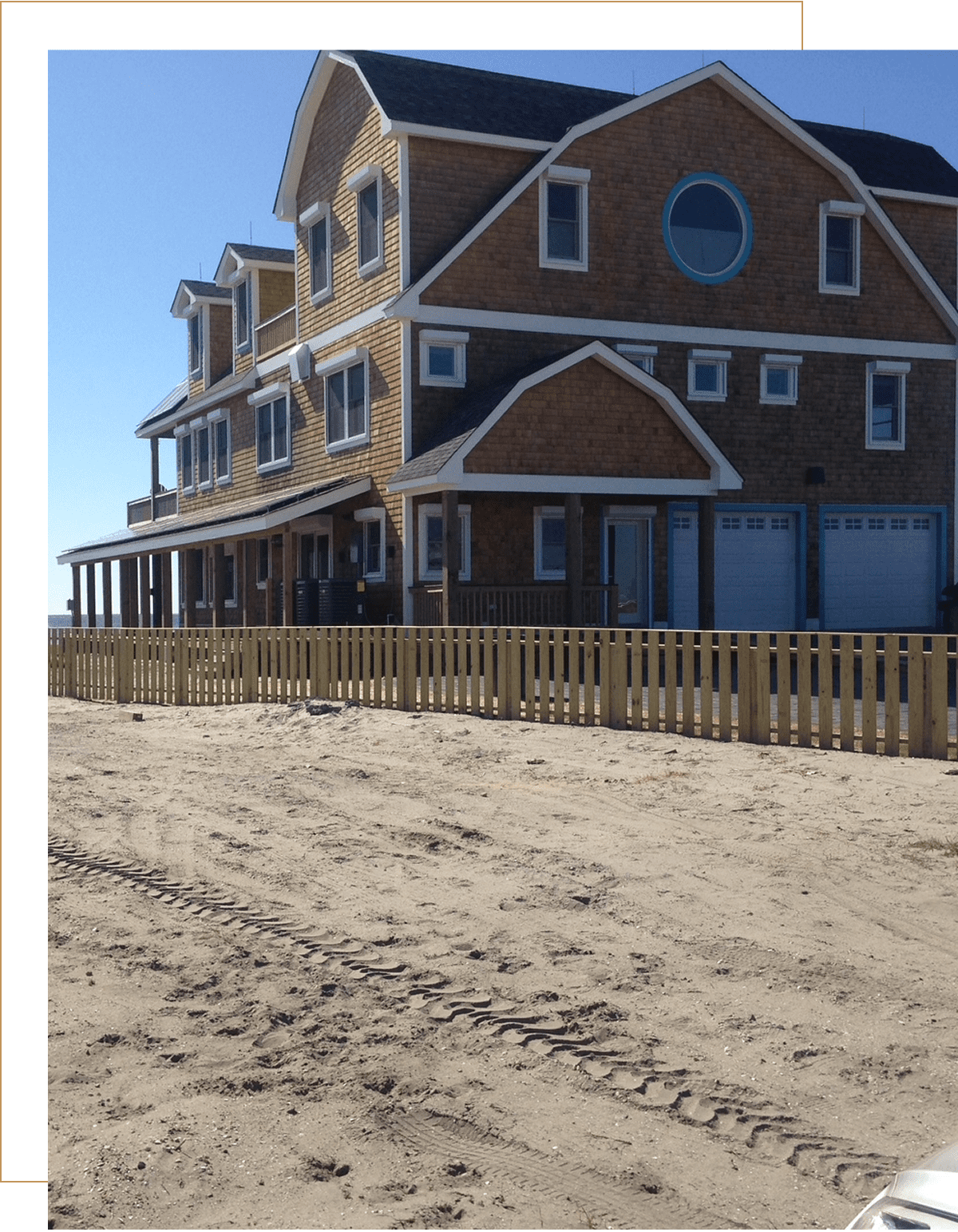 Large beach house with wooden fence.